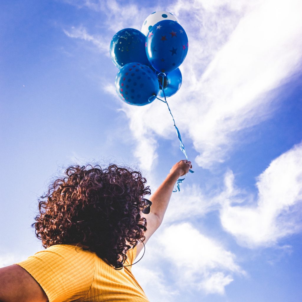 Woman holding up 4 blue balloons
