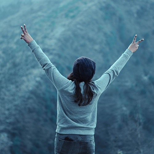 Woman facing mountain making two peace signs