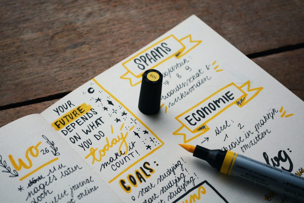 Yellow marker resting on journal filled with motivational goals