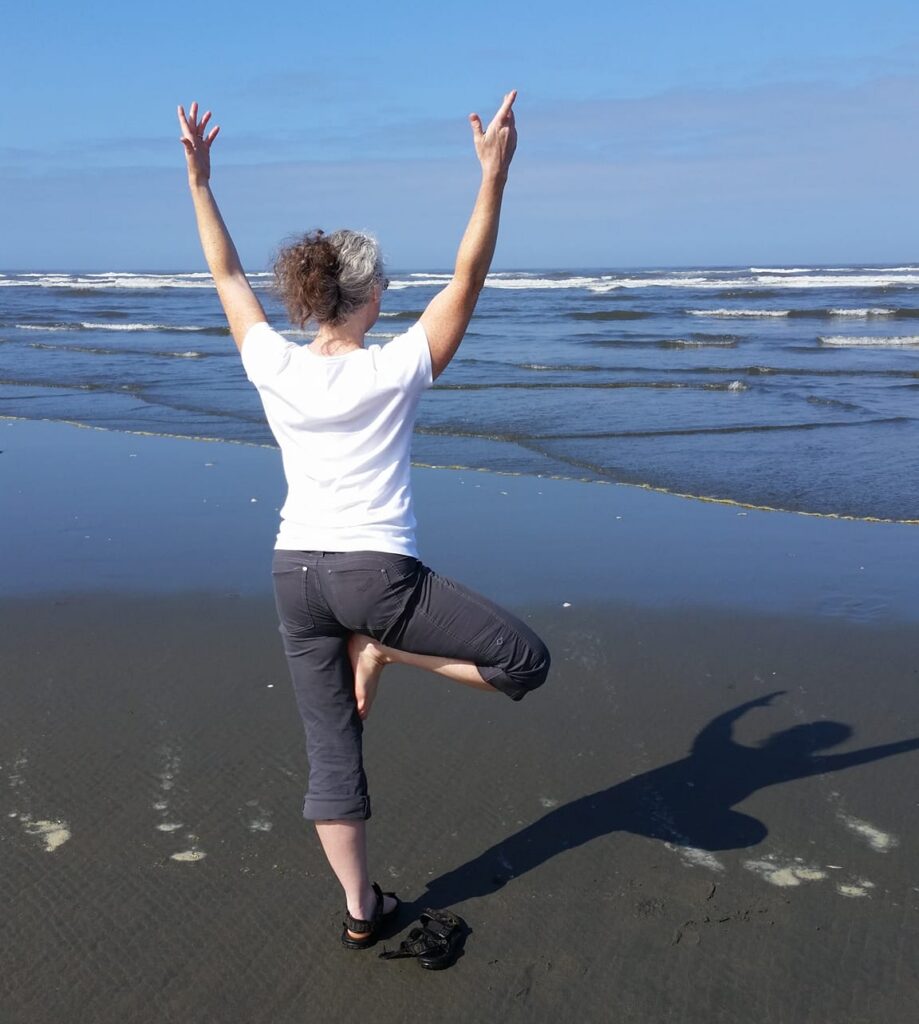 Woman in standing tree pose on the beach